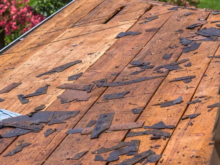 A stripped roof deck showing rotted planking and old shingle before replacement